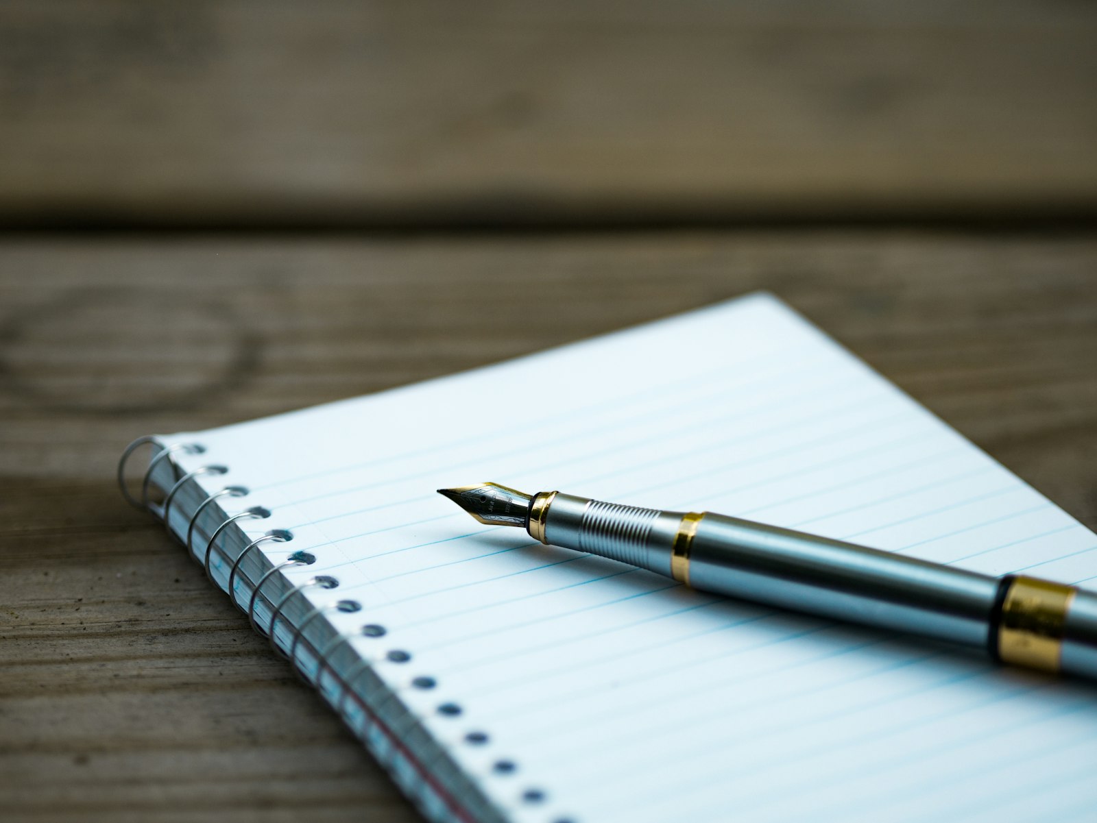 A fountain pen resting on a spiral notebook