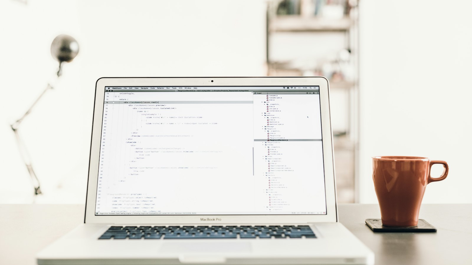 A laptop on a desk beside a mug of coffee