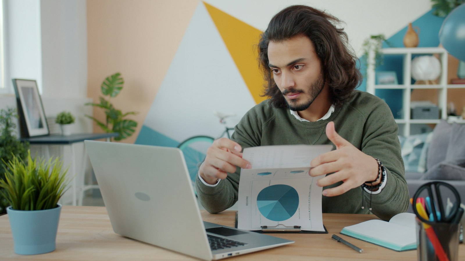 A shop owner at a laptop holding up a printed pie chart