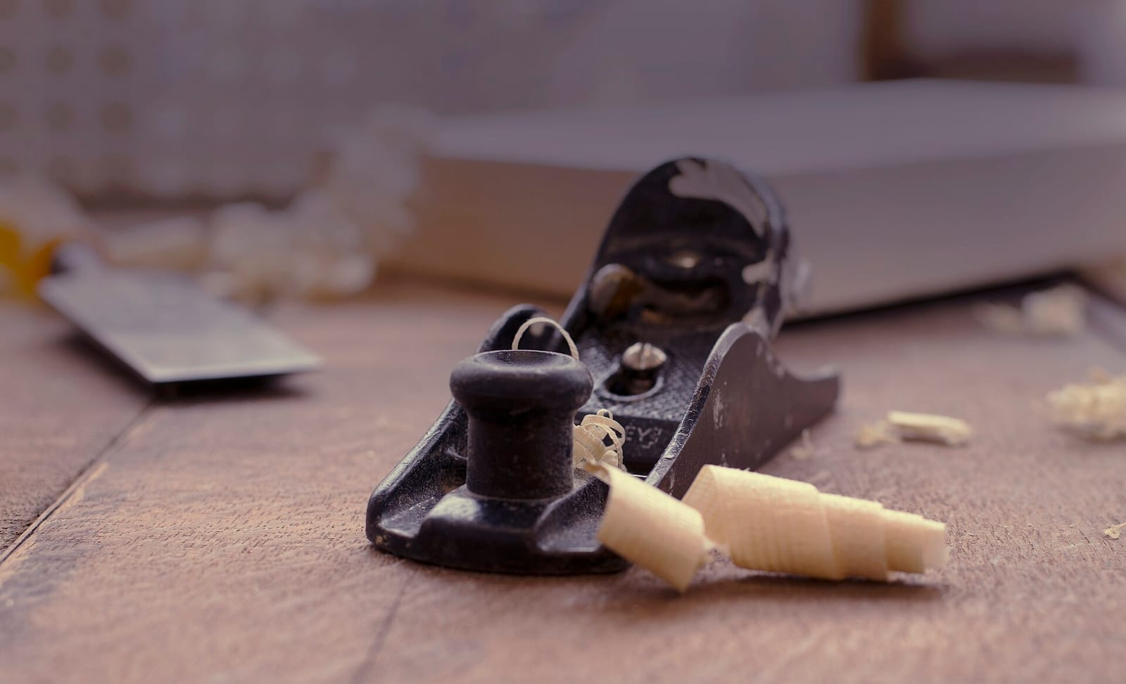 A hand plane on a workbench among wood shavings