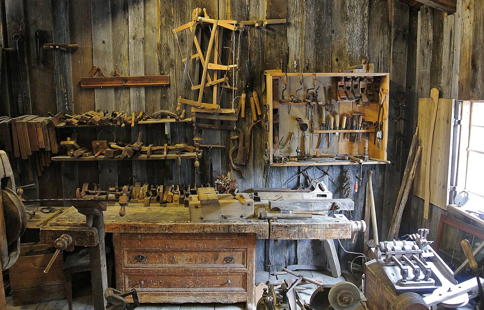 A wall of hand tools hanging above a wooden workbench